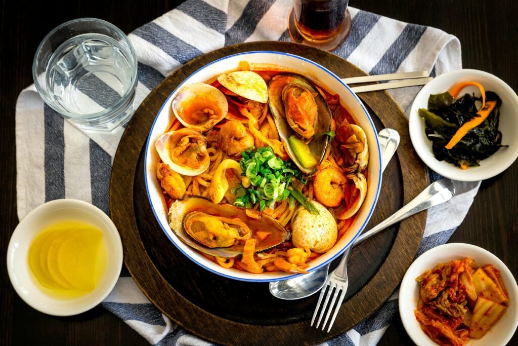 Seafood Delicacy on Bowl Near Gray Stainless Steel Fork, Spoon, Chopsticks, Beside Water in Drinking Glass on Table