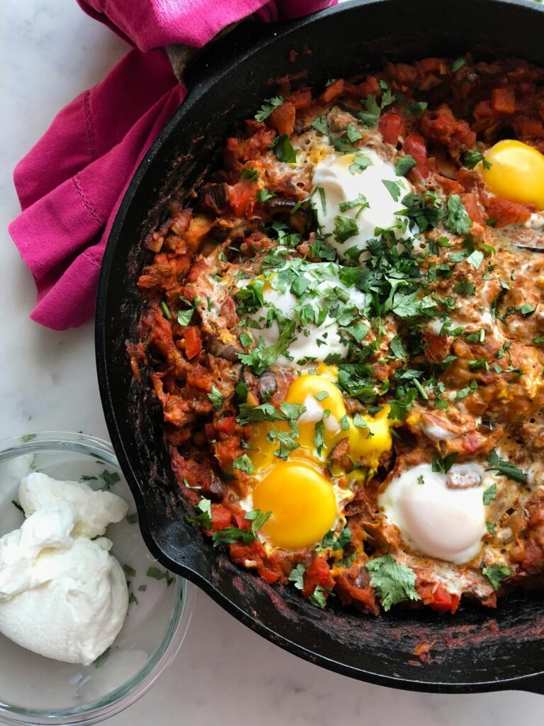 Cooking Shakshuka with red peppers and tomatoes from Jerusalem: A Cookbook for a cookbook review on the blog. Delicious brunch, made even better with homemade harissa and labneh.