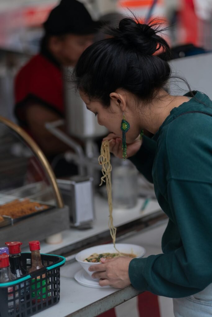 Woman Eating Ramen with Chopsticks While Standing