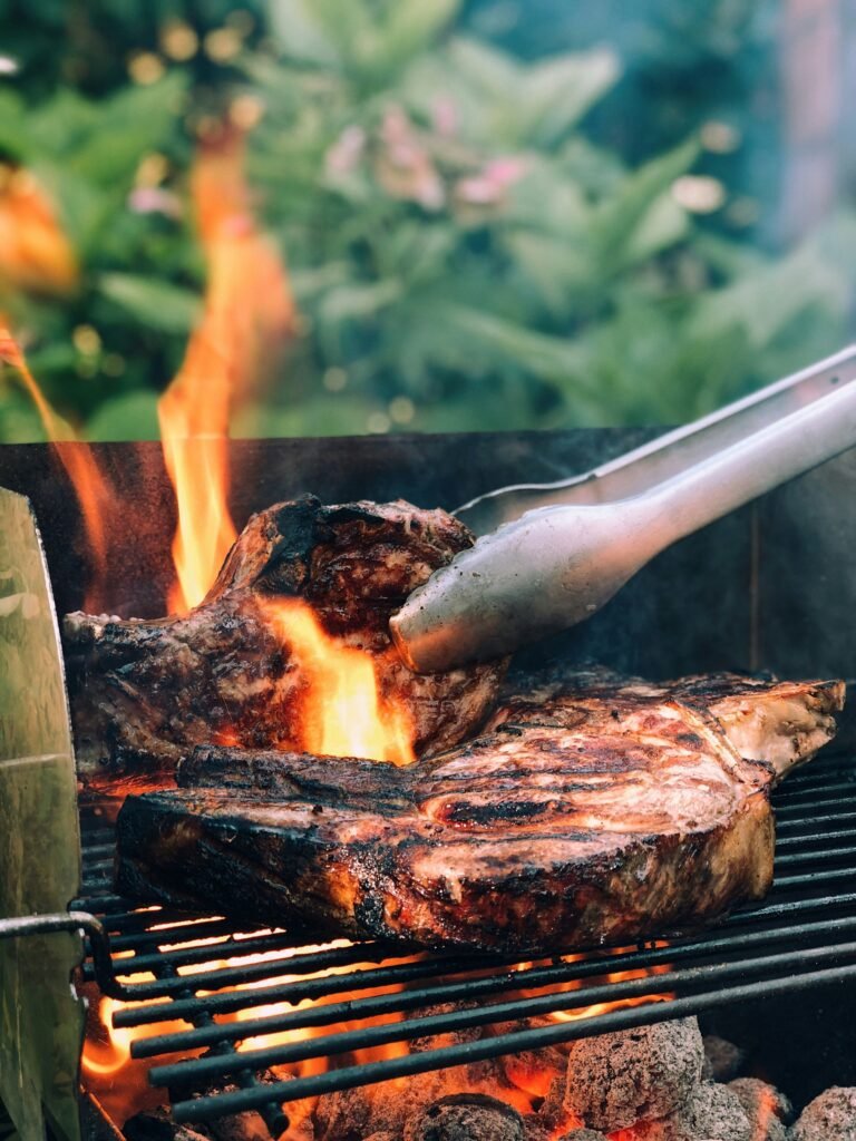 gray-metal-tong-and-grilled-meat-with-fire