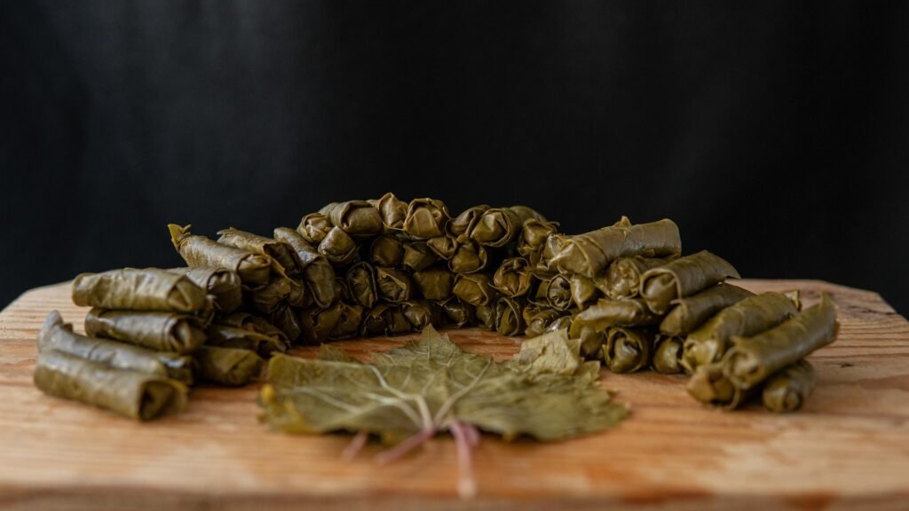 Dolma rolls near grape leaf on table